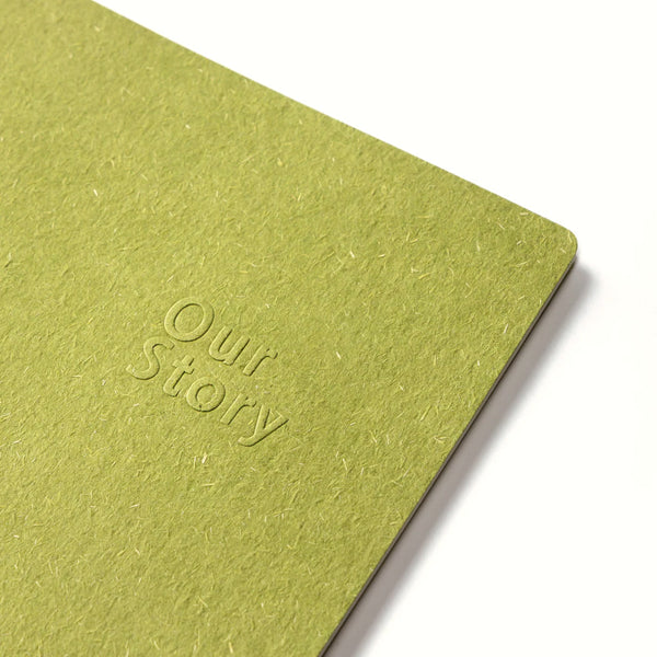 Green notebook with 'Our Story' embossed on the cover against a white background