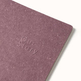 Violet notebook with 'Our Story' embossed on the cover