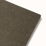 Dark brown notebook with 'Our Story' embossed on it, on a light gray background