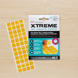 Tombow Xtreme adhesive tabs packaging with yellow tabs on a wooden surface